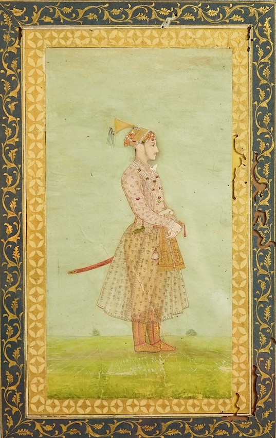 Mogul (Mughal) School , Profile Portrait of a Mogul dignitary, possibly Shah Jahan (1592-1666), full length, wearing court attire and a sword, standing in a landscape, watercolour miniature, 31cm x 20.5cm including borde